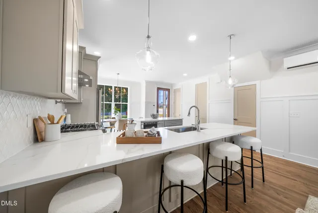 a kitchen with stainless steel appliances a dining table chairs sink and cabinets