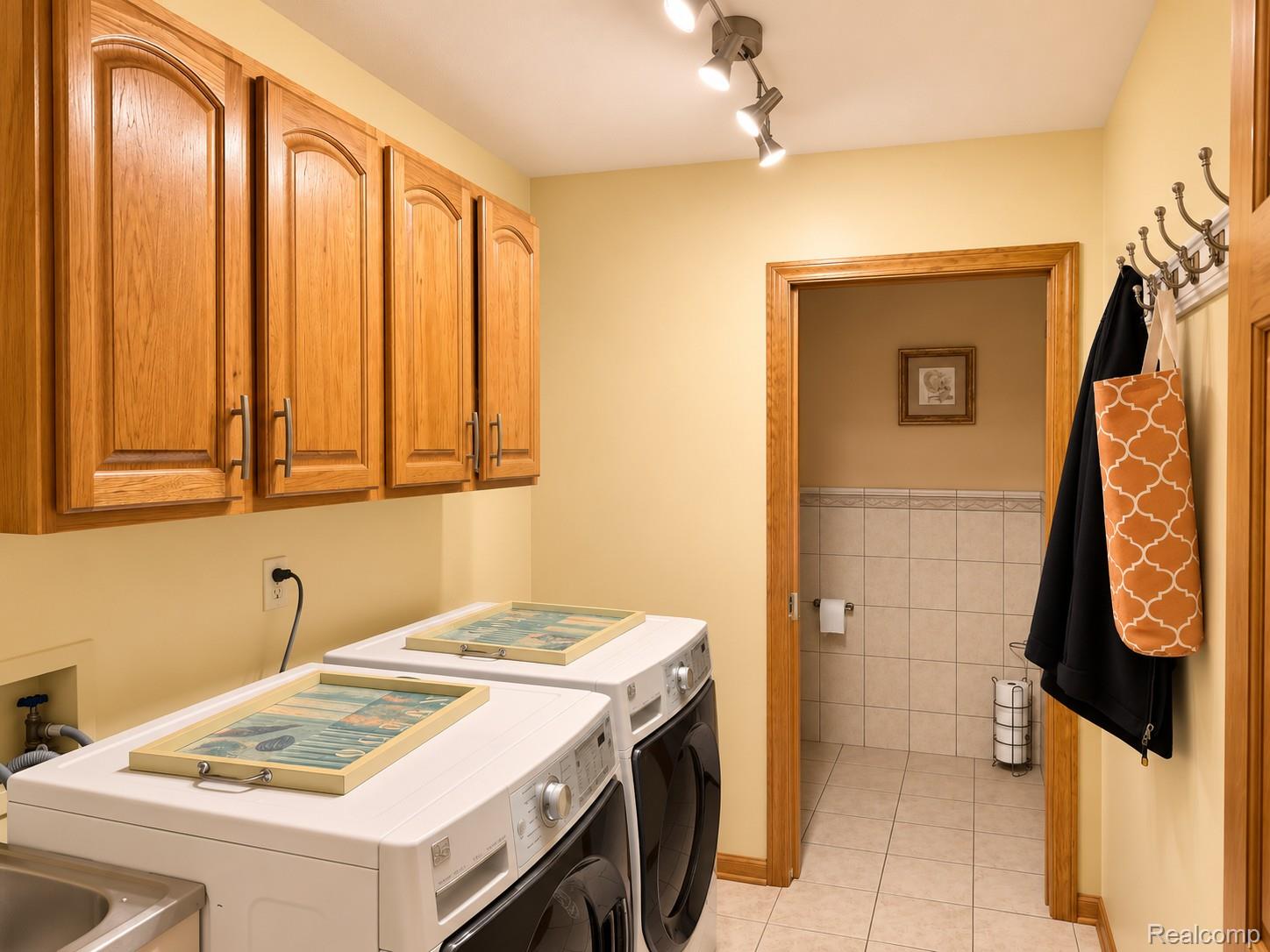 2495 North Custer Road Monroe, MI 48162 - Photo 18 of 44 Laundry room featuring wood cabinetry, track lighting, and a utility sink