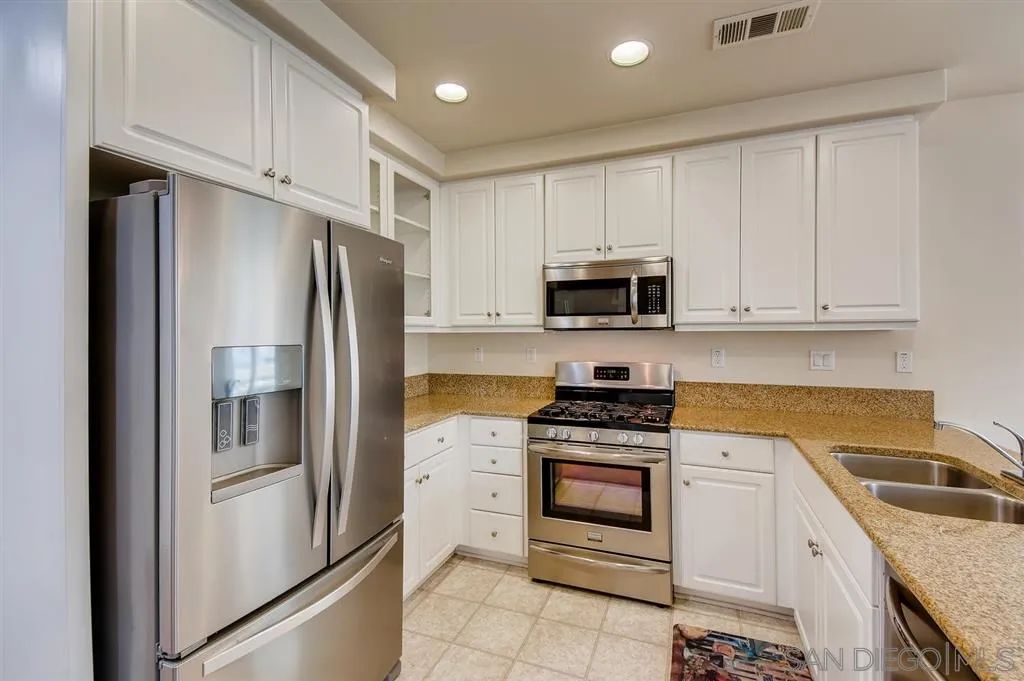 1435 Santa Diana Road, Unit 9 Chula Vista, CA 91913 - Photo 5 of 23 a kitchen with white cabinets and stainless steel appliances