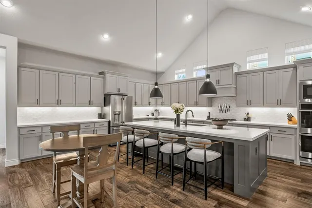 a kitchen with stainless steel appliances a table chairs refrigerator and microwave