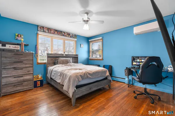 a bedroom with a bed a desk and chair with wooden floor