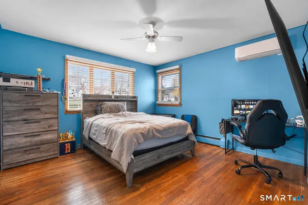 a bedroom with a bed a desk and chair with wooden floor