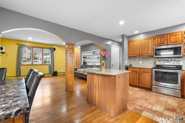 a kitchen with stainless steel appliances granite countertop a stove top oven a sink dishwasher a dining table and chairs with wooden floor