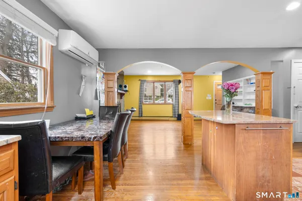 a dining hall with stainless steel appliances granite countertop a stove and a wooden floors