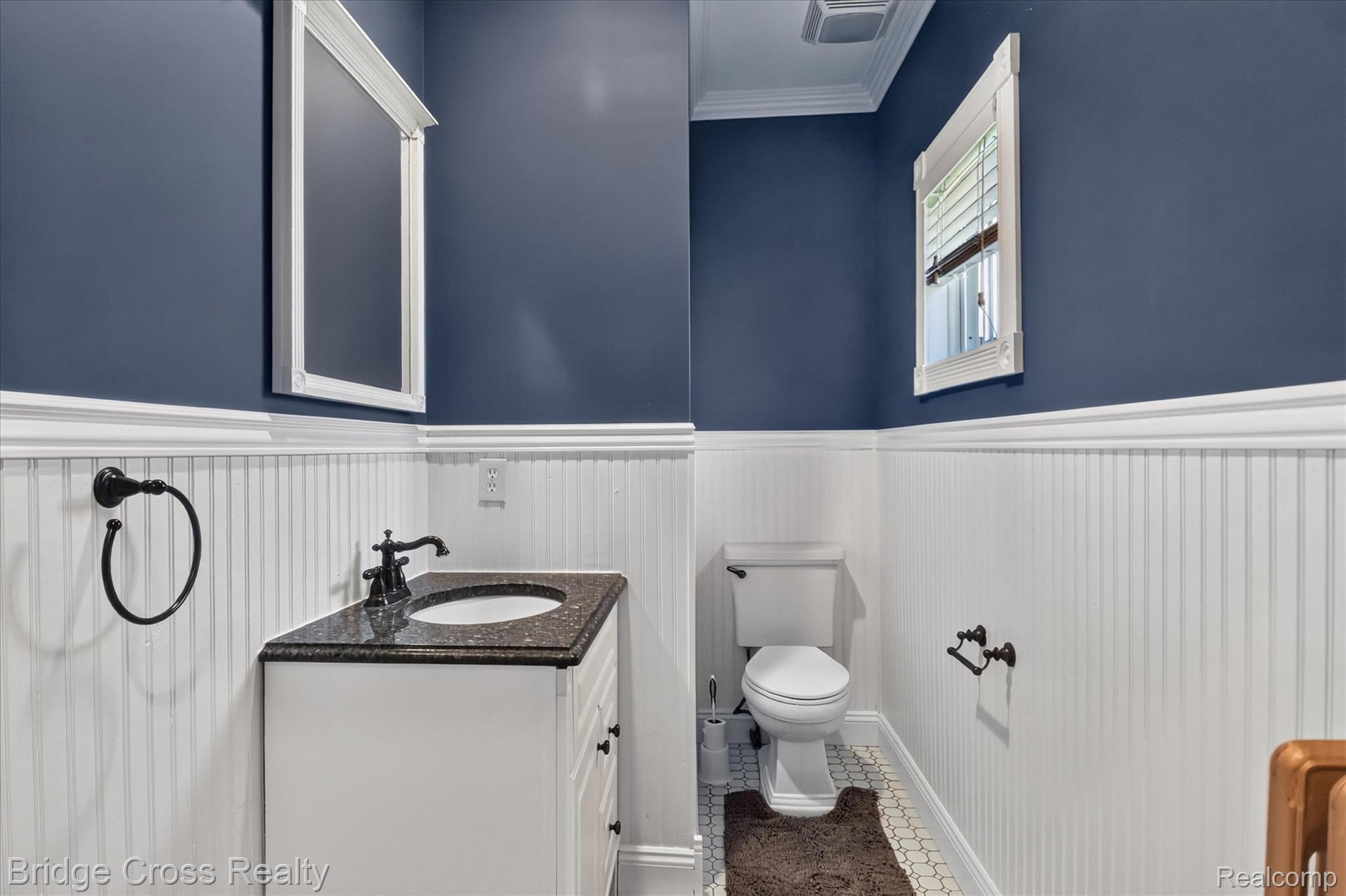 285 East Long Lake Road Troy, MI 48085 - Photo 33 of 49 Vanity with dark countertop, white beadboard wainscoting, white framed mirror, and crown molding