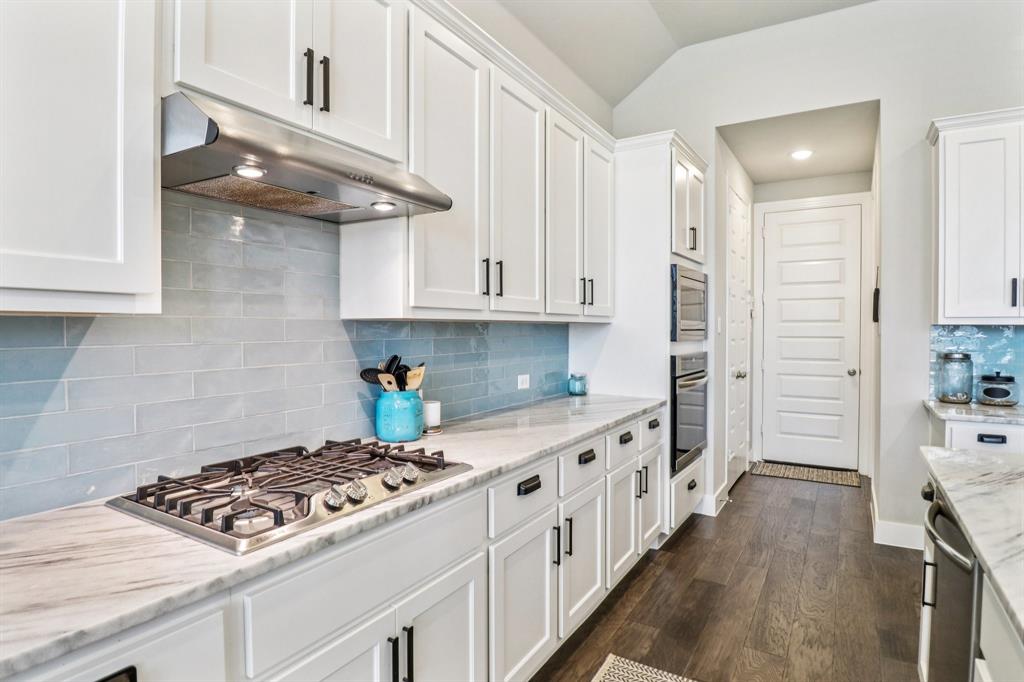 847 Longbranch Way Little Elm, TX 76227 - Photo 11 of 39 Kitchen featuring backsplash, white cabinets, under cabinet range hood, appliances with stainless steel finishes, and dark wood finished floors