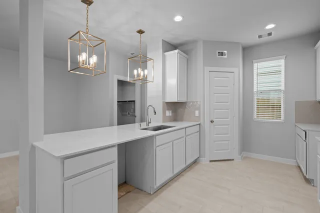 a room with white cabinets and chandelier