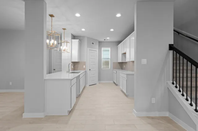 a large kitchen with a sink and dishwasher a refrigerator with white cabinets