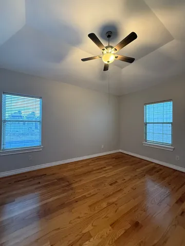 a view of an empty room with a window and wooden floor