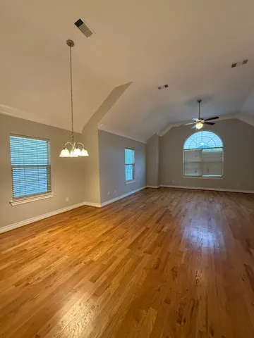 a view of an empty room with window and wooden floor