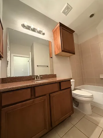 a bathroom with a granite countertop toilet sink and mirror