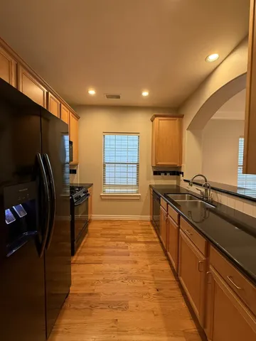 a large kitchen with stainless steel appliances a large counter top a stove a chimney a sink and a refrigerator