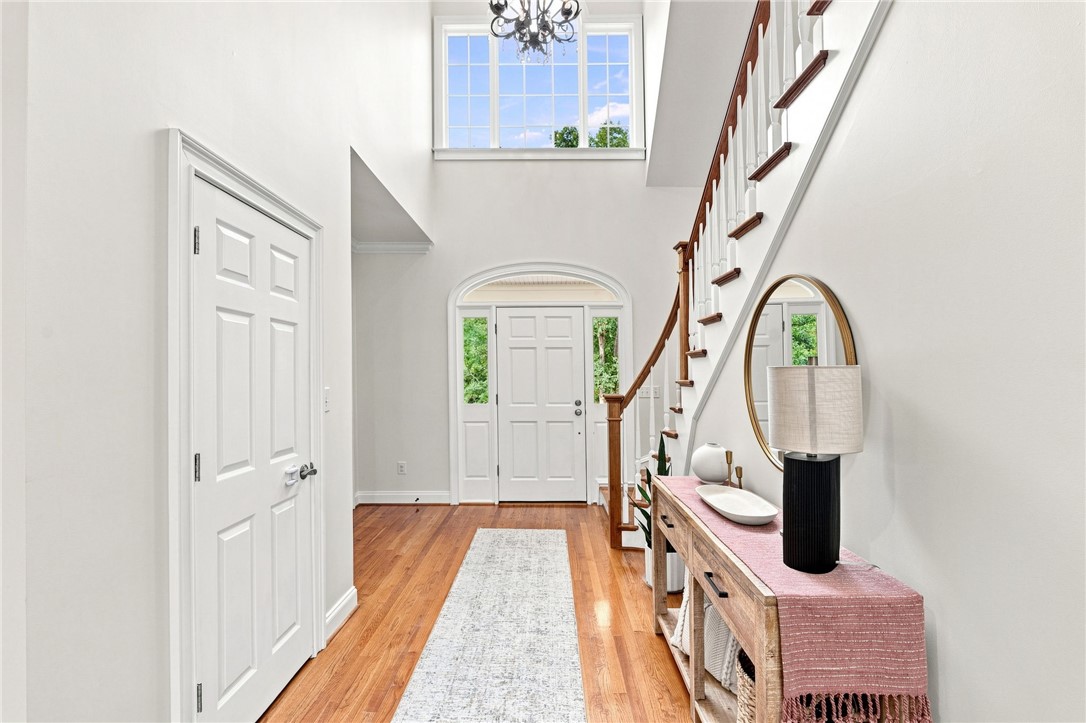 Rich hardwood floors welcome visitors into a double-height entryway featuring a classic staircase.