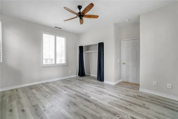 an empty room with wooden floor fan and windows