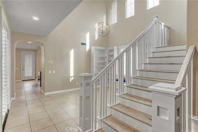 a view of staircase with white walls and chandelier