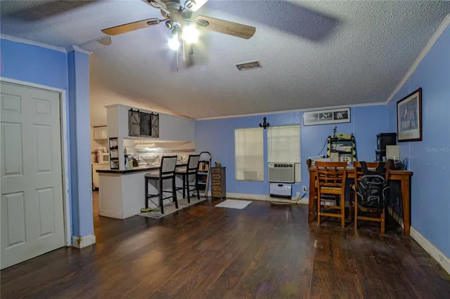 a kitchen with stainless steel appliances a refrigerator a stove top oven a dining table and chairs with wooden floor