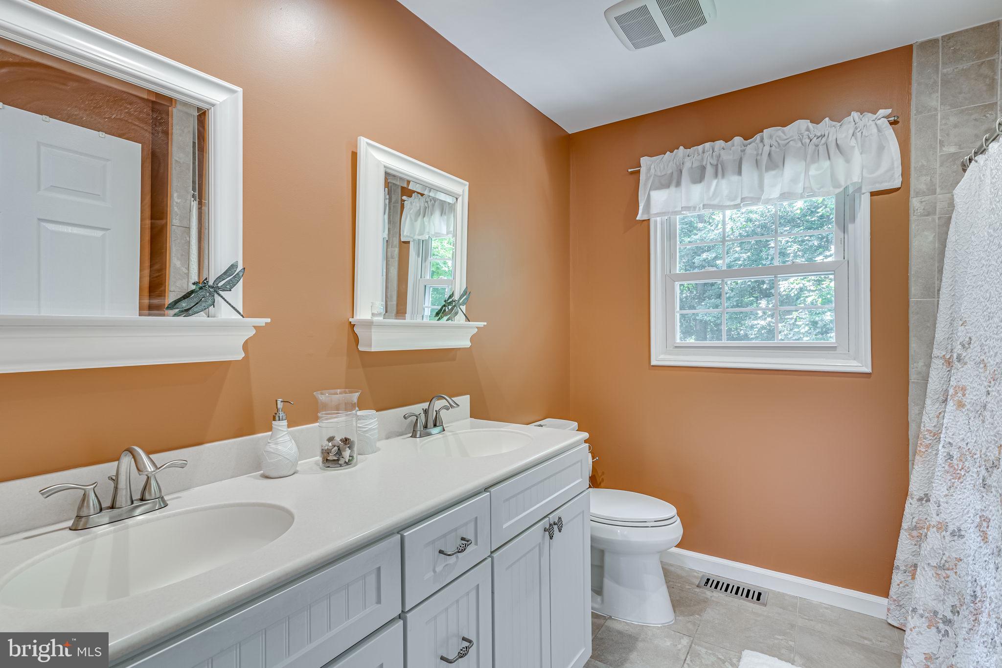 9741 Howes Road Dunkirk, MD 20754 - Photo 33 of 48 a bathroom with a toilet a sink a mirror and a window