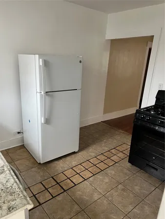a view of a refrigerator in kitchen and an empty room