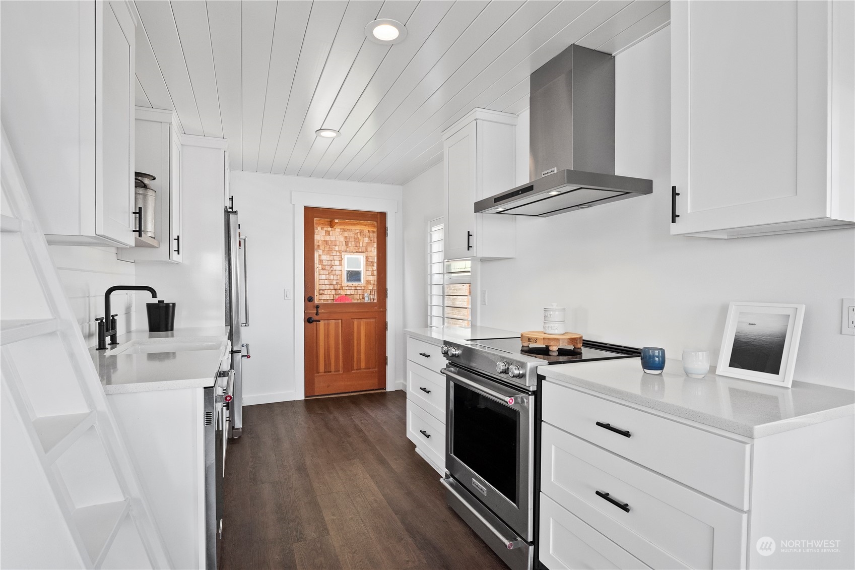 8003 Possession Beach Walk Clinton, WA 98236 - Photo 10 of 31 a kitchen with stainless steel appliances granite countertop a stove a sink dishwasher and white cabinets with wooden floor