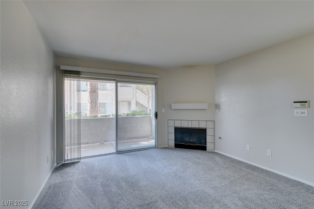 5211 Caspian Springs Drive, Unit 101 Las Vegas, NV 89120 - Photo 11 of 37 Unfurnished living room with a tile fireplace and carpet flooring