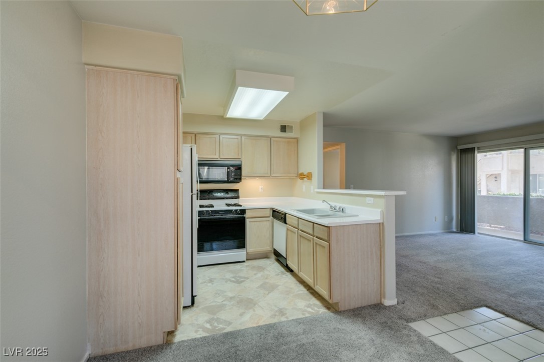 5211 Caspian Springs Drive, Unit 101 Las Vegas, NV 89120 - Photo 36 of 37 Kitchen featuring light brown cabinetry, light carpet, light countertops, open floor plan, and white appliances