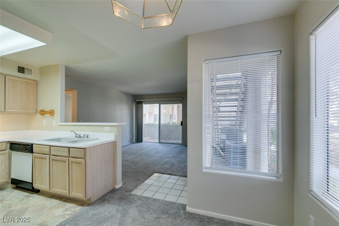 5211 Caspian Springs Drive, Unit 101 Las Vegas, NV 89120 - Photo 21 of 37 Kitchen with light brown cabinets, light countertops, light carpet, and a peninsula