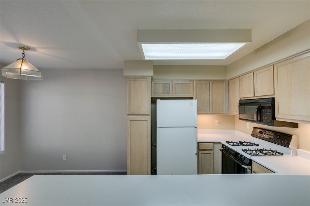 5211 Caspian Springs Drive, Unit 101 Las Vegas, NV 89120 - Photo 23 of 37 Kitchen featuring gas range, freestanding refrigerator, light countertops, and light brown cabinets