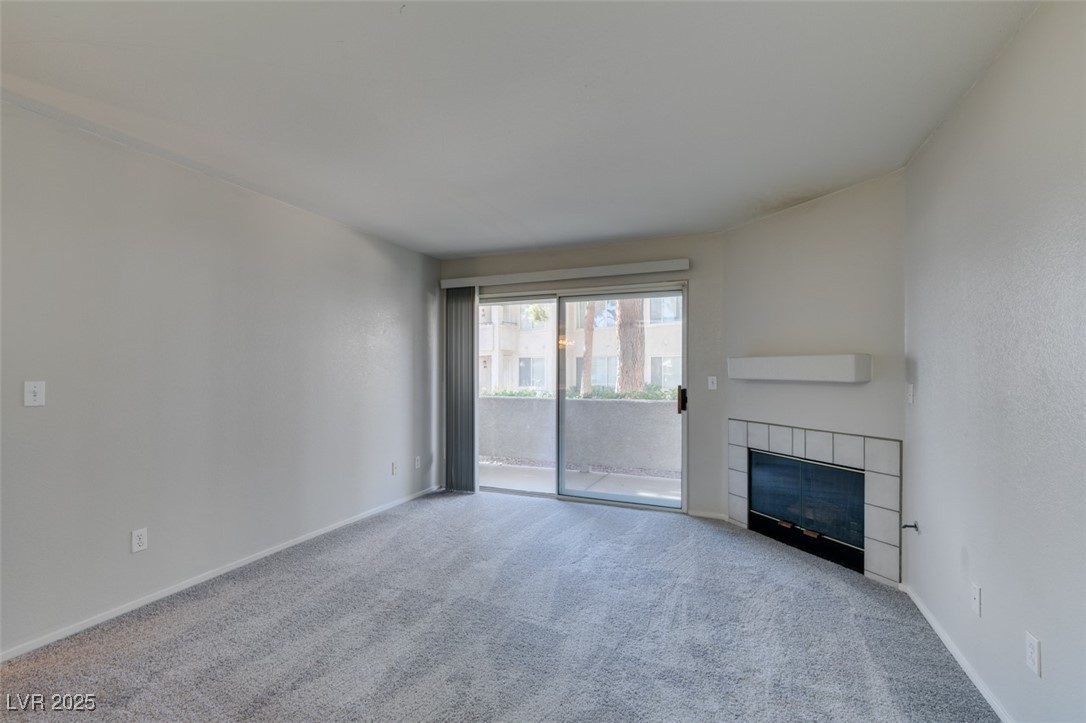5211 Caspian Springs Drive, Unit 101 Las Vegas, NV 89120 - Photo 7 of 37 Unfurnished living room featuring carpet flooring and a fireplace