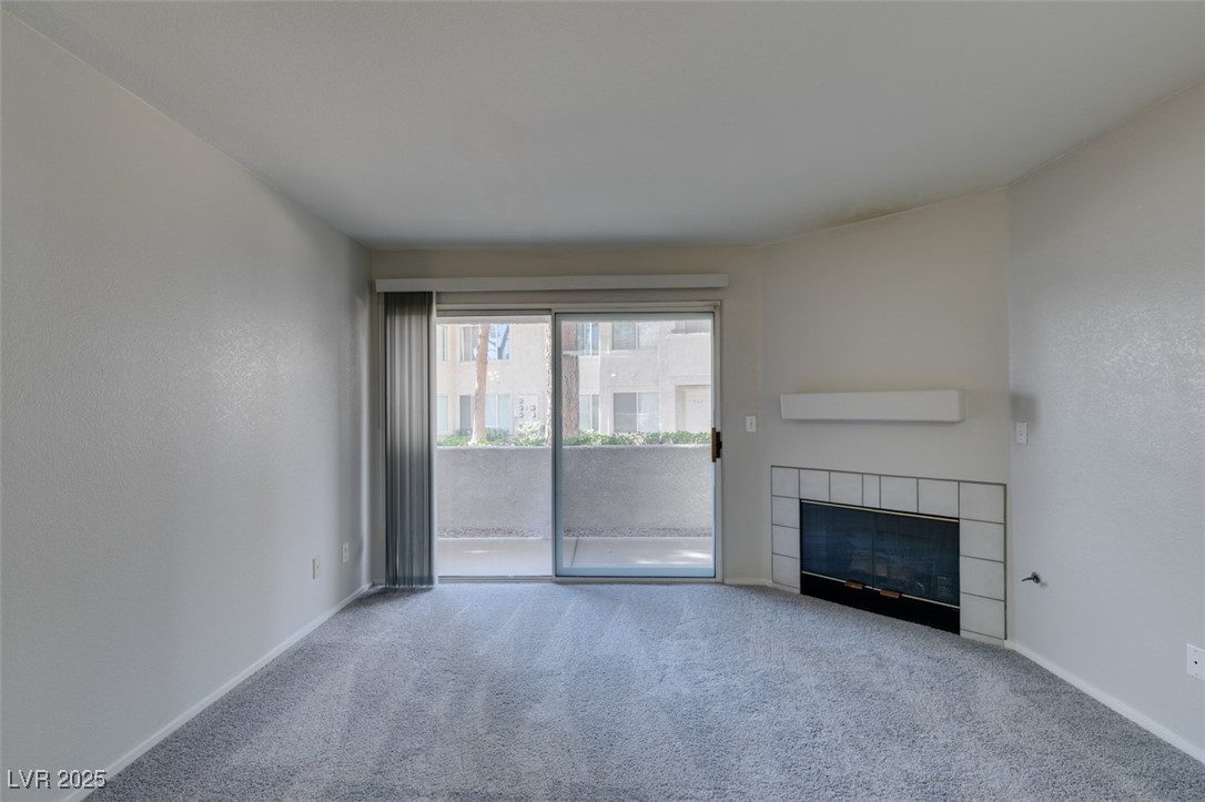 5211 Caspian Springs Drive, Unit 101 Las Vegas, NV 89120 - Photo 10 of 37 Unfurnished living room with carpet flooring, a fireplace, and a textured wall