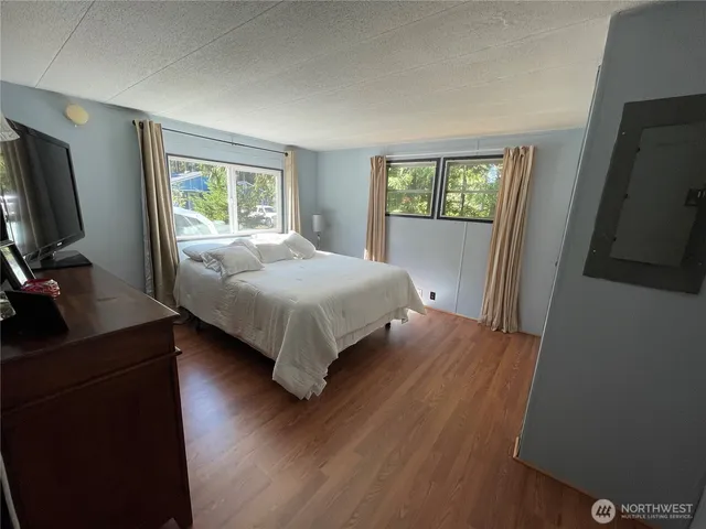 a bedroom with a bed wooden floor and a flat tv screen on a dresser