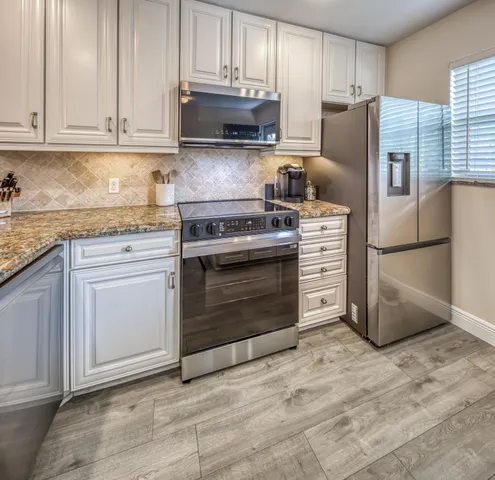 a kitchen with granite countertop a stove a sink and a wooden floors