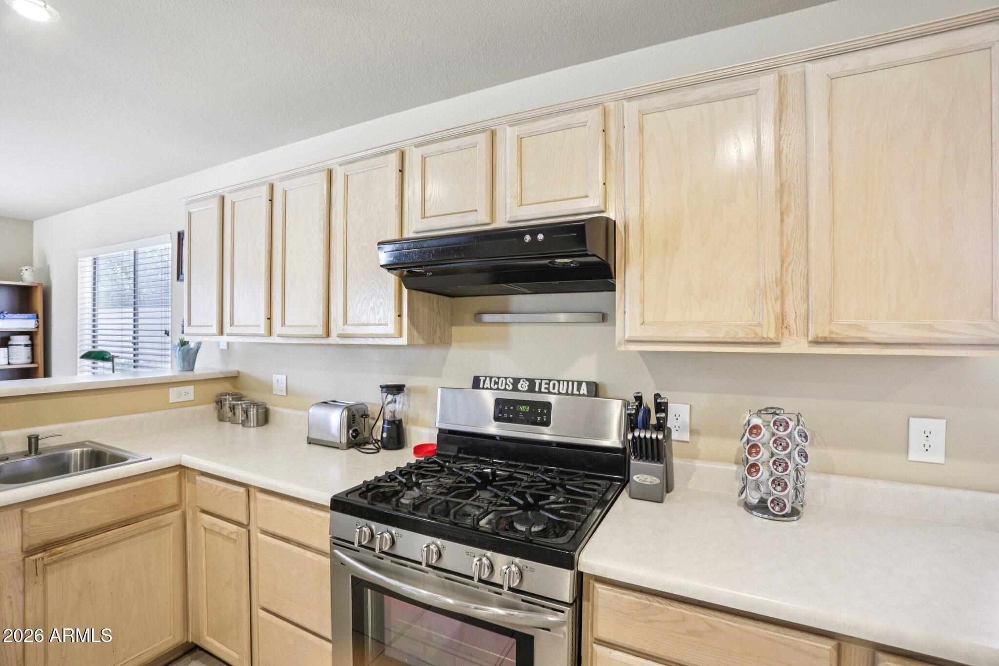 13414 South 47th Way Phoenix, AZ 85044 - Photo 12 of 32 a kitchen with granite countertop a stove a sink dishwasher and cabinets with wooden floor