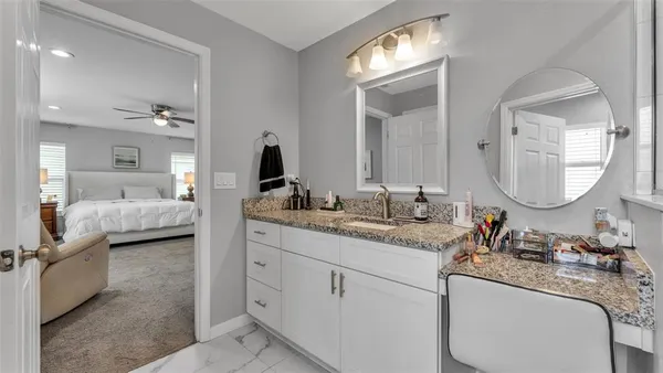 a en suite bathroom with a granite countertop double sink and a mirror