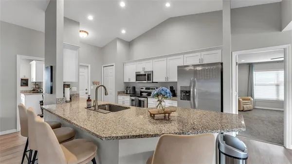 a kitchen with granite countertop a table chairs microwave and refrigerator