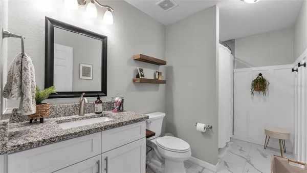 a bathroom with a granite countertop sink mirror and toilet