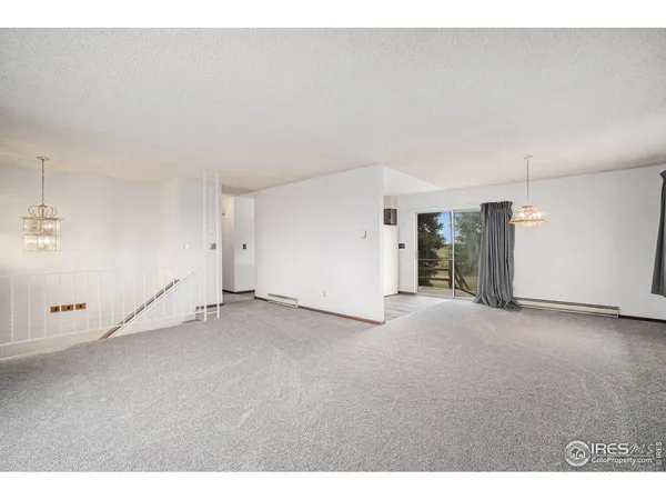 a view of a big room with wooden floor and a kitchen space