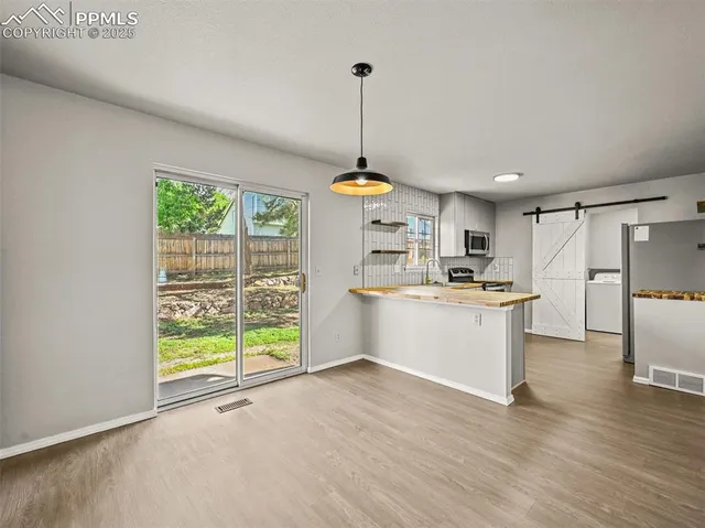 a kitchen with refrigerator and wooden floor