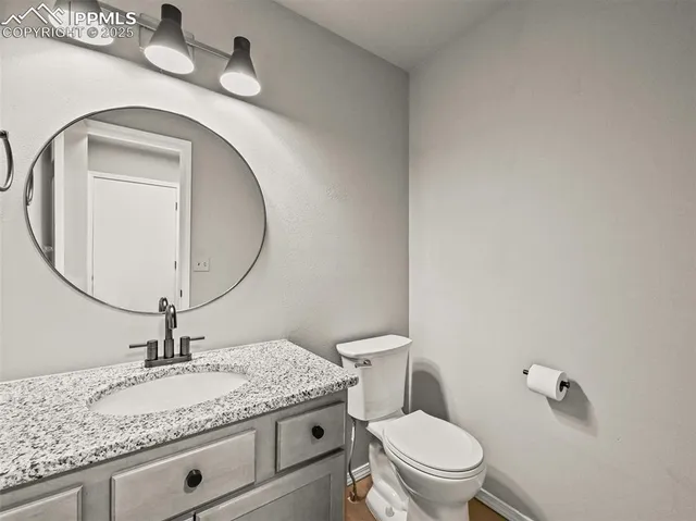 a bathroom with a granite countertop toilet a sink and mirror