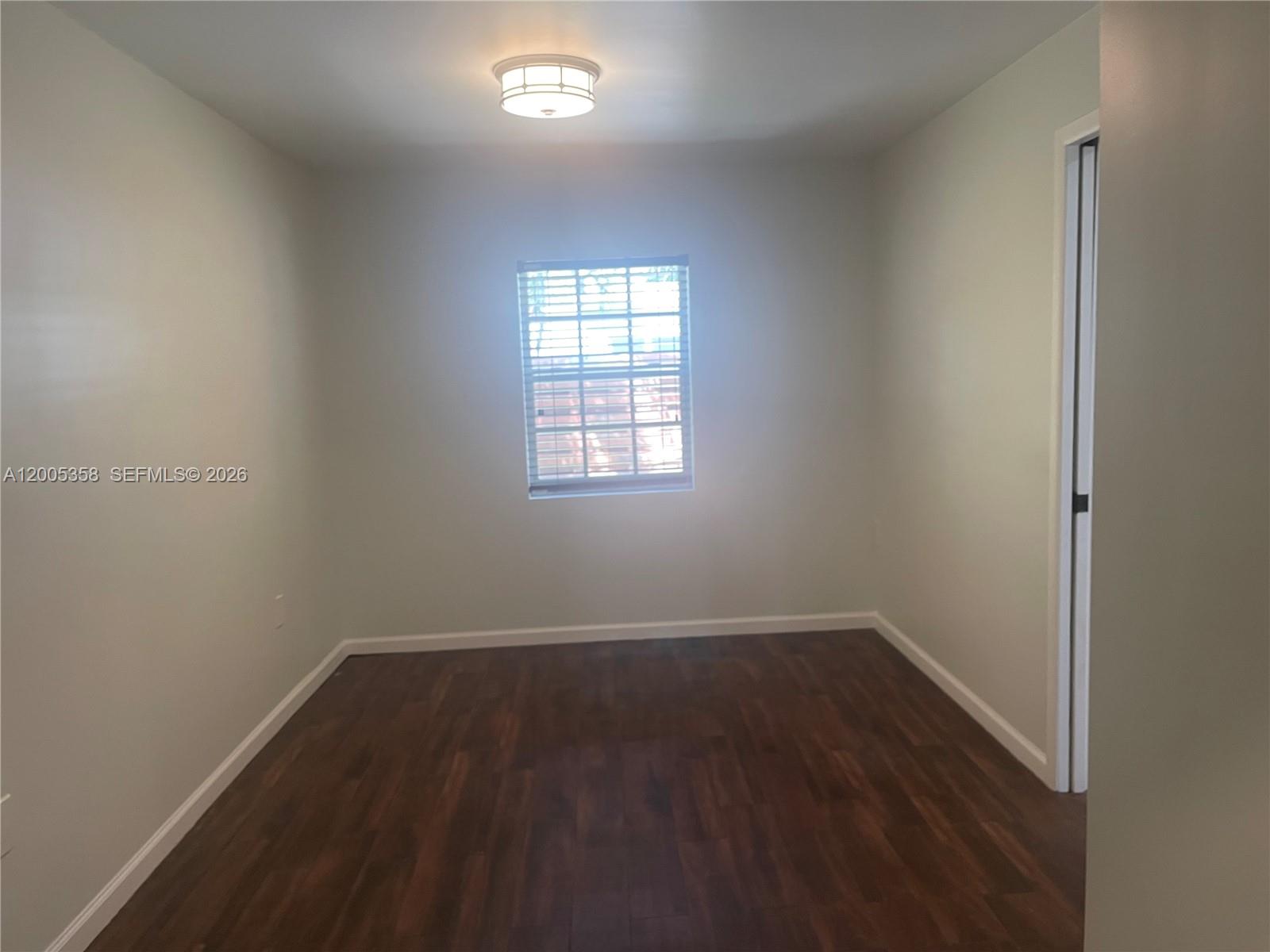 554 Northeast 74th Street, Unit 2 Miami, FL 33138 - Photo 6 of 30 an empty room with wooden floor and windows