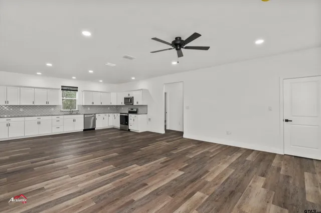a view of a kitchen with a sink and dishwasher with wooden floor