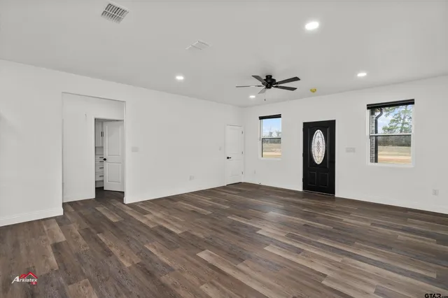 a view of an empty room with a window and wooden floor