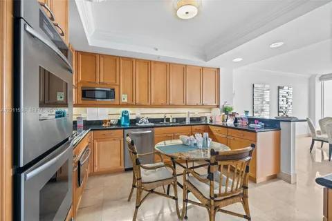 a kitchen with stainless steel appliances granite countertop a stove top oven a sink dishwasher a dining table and chairs with wooden floor
