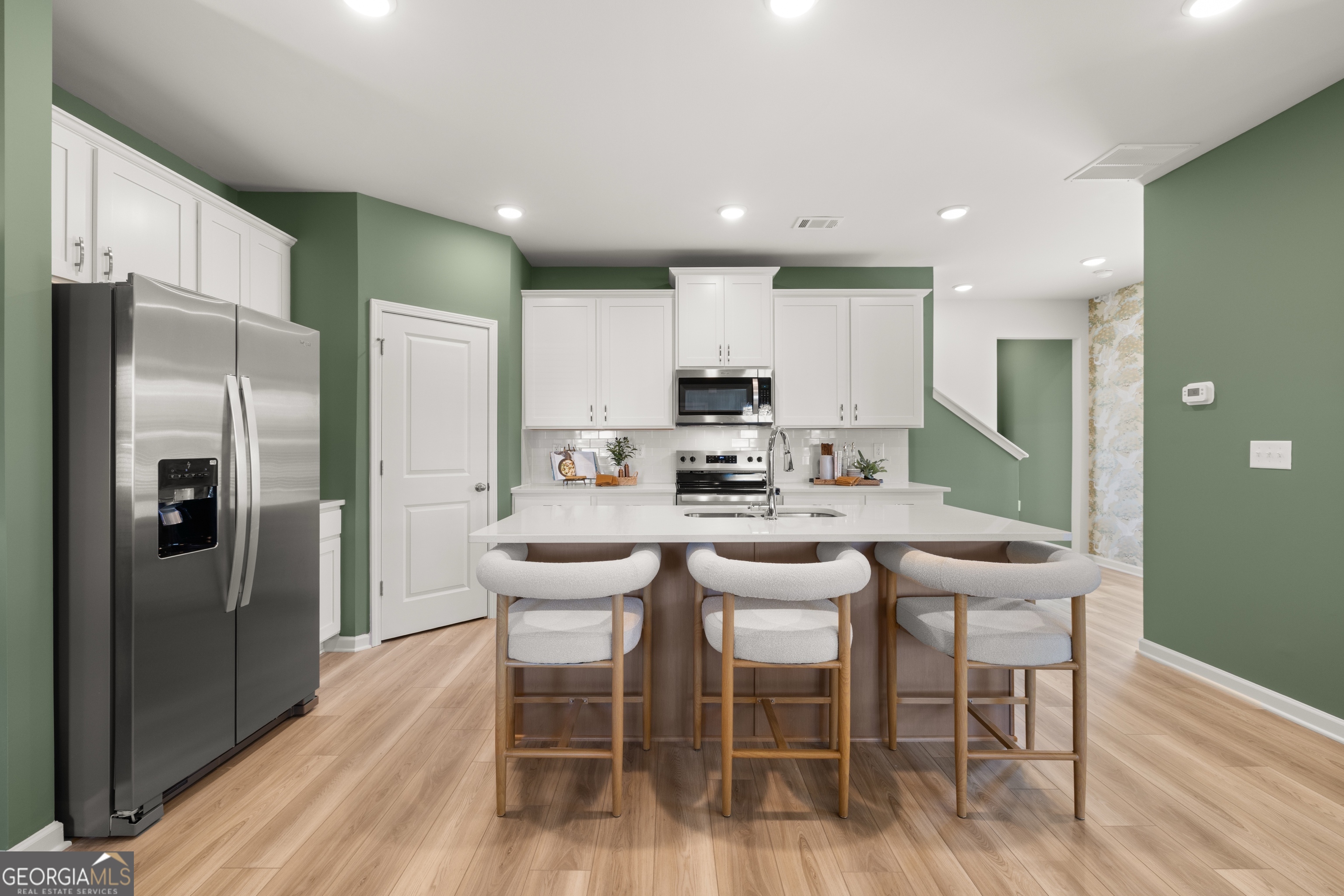 3261 Lake Carlton Road, Unit 24 Loganville, GA 30052 - Photo 5 of 33 a kitchen with stainless steel appliances kitchen island granite countertop a dining table chairs refrigerator and sink