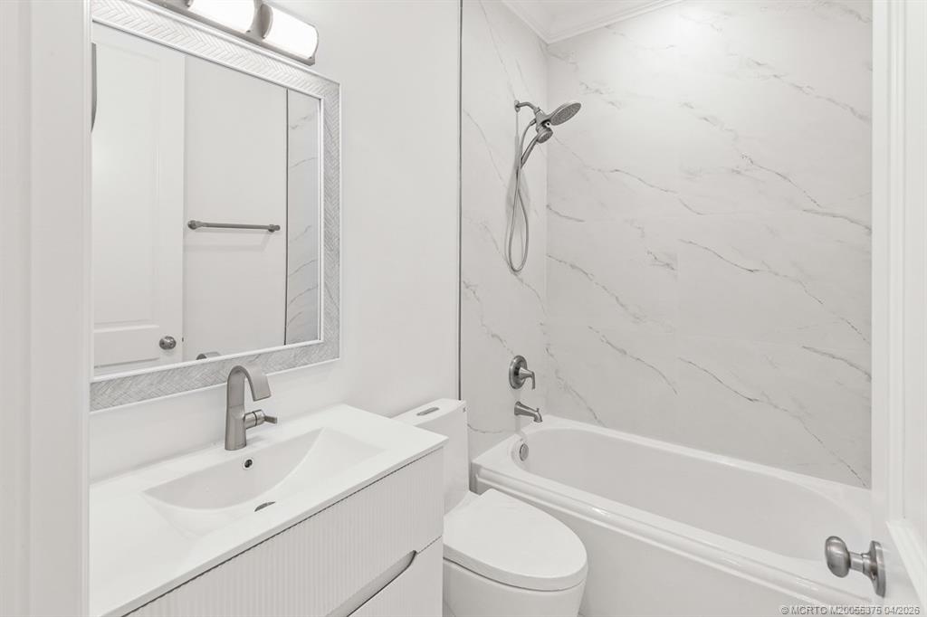 47 Southwest Osceola Street, Unit UN206 Stuart, FL 34994 - Photo 22 of 43 a bathroom with a white bath tub sitting next to a white sink and a white door
