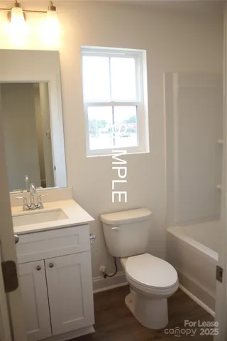 a bathroom with a toilet a sink a mirror and a window
