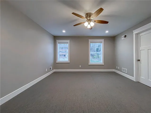 an empty room with windows and fan