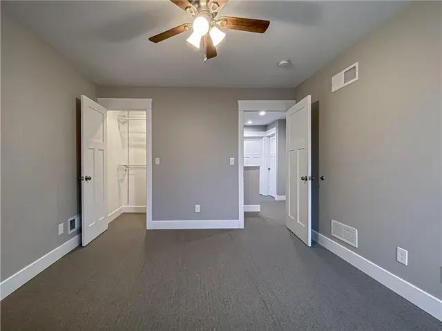 an empty room with closet and a chandelier fan