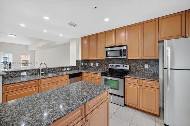 a kitchen with stainless steel appliances granite countertop a stove a sink dishwasher a refrigerator and a microwave