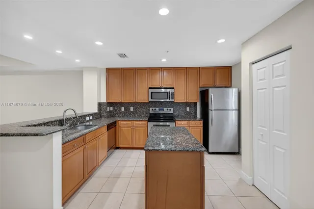 a kitchen with stainless steel appliances granite countertop a refrigerator a stove a sink a microwave and island