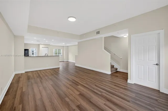 a view of an empty room with wooden floor and windows
